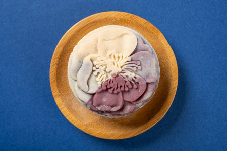 top view trendy and beautiful flower shape purple and white colors moon cake on a blue background
