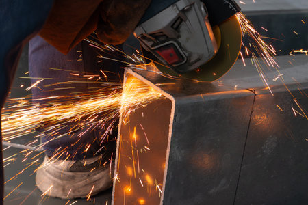 skilled worker cutting an iron pipe with a grinder