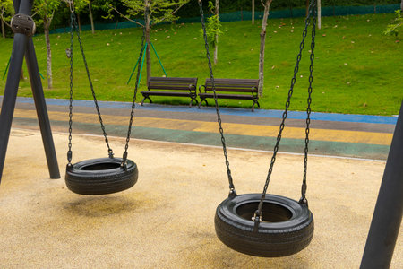 two tire swings hang quietly in a colorful parkの写真素材