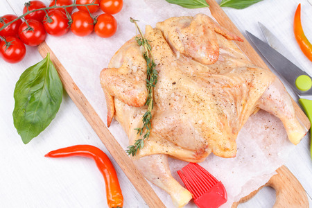 Fresh raw chicken prepared for roast with thyme and tomatoes cherryの写真素材