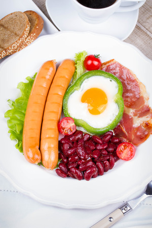 Egg fried in a green pepper, sausages, bacon and red beansの写真素材