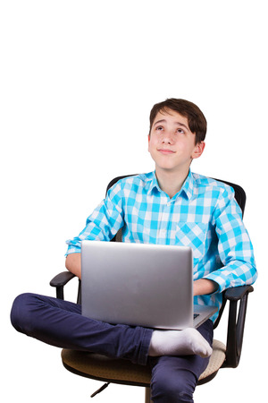 Working on laptop. Teenager sitting on a chair and looking up isolated on white backgroundの写真素材