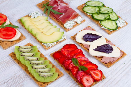 Fresh healthy appetizer snack with crispbread, fruits, berries, hamon and cheeseの写真素材