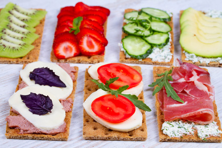 Fresh healthy appetizer snack with crispbread, fruits, berries, hamon and cheeseの写真素材