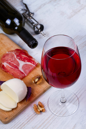 Glass and bottle of wine, cheese and prosciuttoの写真素材