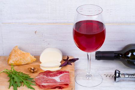 Glass and bottle of wine, cheese and prosciuttoの写真素材