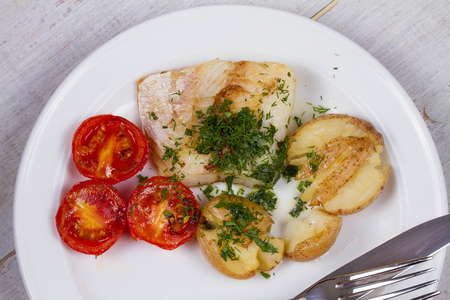 Fish Fillets with Herbs, Crispy Potatoes and  Roasted Tomatoesの写真素材