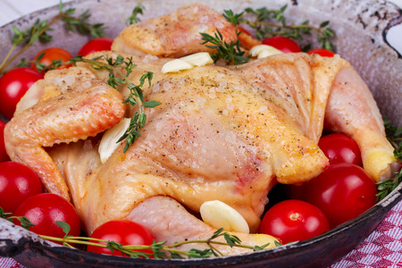 Whole fresh raw chicken prepared for roast with thyme and tomatoes cherryの写真素材
