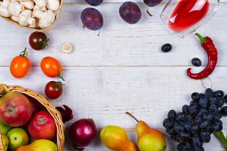 Mushrooms, grape, plums, onion, tomatoes, chilli peppers, glass of red wine, apples and pears in basket. View from above; top studio shotの写真素材