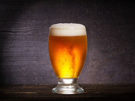 Glass of beer against dark wooden background, with copyspaceの写真素材