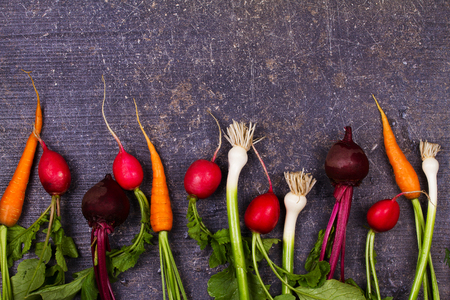 Vegetables on old  dark desk: baby carrot, garlic, beetroot, radishes. View from above, top studio shotの写真素材