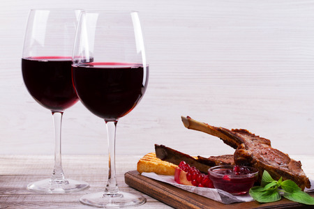 Red wine glasses. Rack of lamb with pomegranate sauce and greensの写真素材