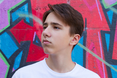 Teen boy next to graffiti painted wall. Outside portrait of teenager.の写真素材