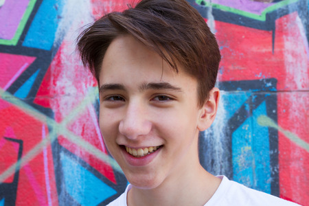 Teen boy next to graffiti painted wall. Outside portrait of teenager.の写真素材