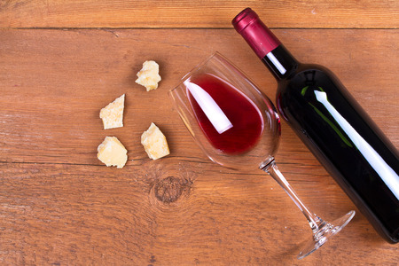 Glass and bottle of red wine with parmesan. Wine and cheese still life. View from above, top studio shotの写真素材