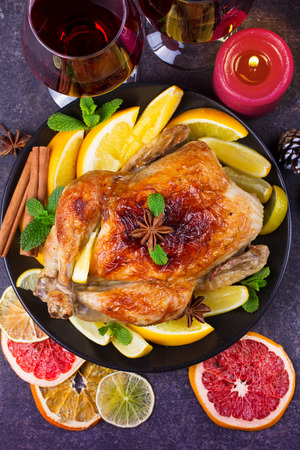 Festive Christmas turkey baked with orange, lemon and lime. Glasses of red wine and candles. View from above, top studio shotの写真素材