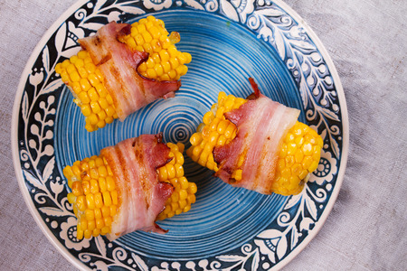 Bacon wrapped corn on blue plate. View from above, top studio shotの写真素材