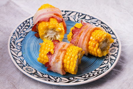 Bacon wrapped corn on blue plateの写真素材
