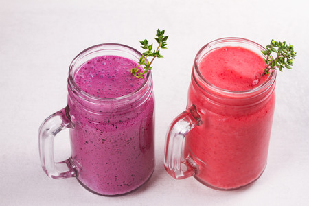 Summer berries smoothie in the jars on white rustic backgroundの写真素材