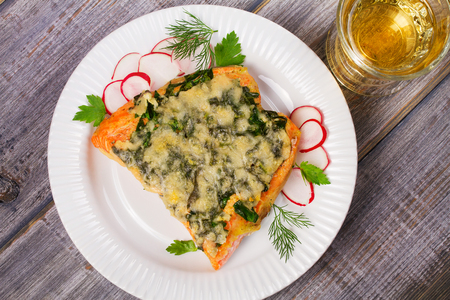 Baked salmon with spinach and cheese. Fish on white plate.の写真素材