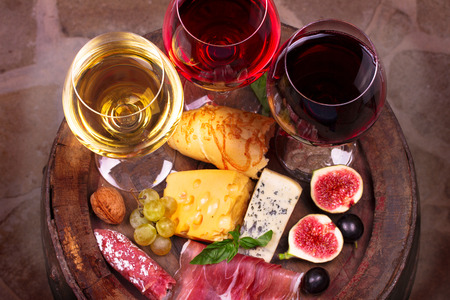 Glasses of red, rose and white wine with grape, figs and walnuts in wine cellar. Food and drinks concept. View from above, top studio shotの写真素材
