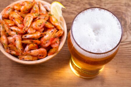 Glass of beer and shrimps on wooden background. View from above, top studio shotの写真素材
