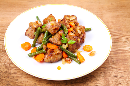 Beef liver with vegetables: carrot, onion and green beans on white plate, horizontalの写真素材