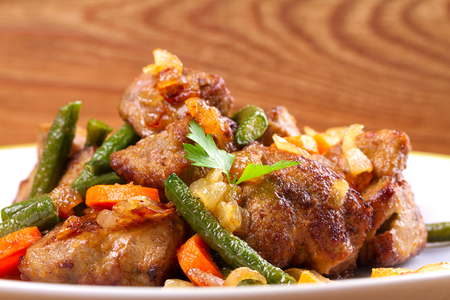 Beef liver with vegetables: carrot, onion and green beans on white plate, horizontalの写真素材