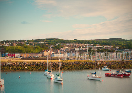Small town on sea coast. Beautiful landscape of fishing town. Boats and yachts in Howth harbor in summer. Suburb of Dublin, Ireland. Lightly tonedの写真素材