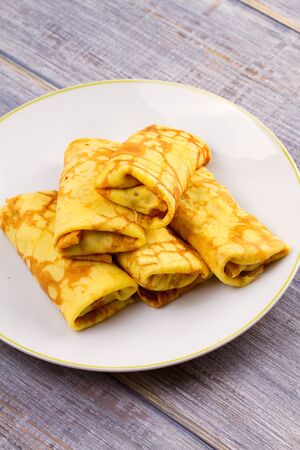 Wrapped thin pancakes  filled with mushrooms on white plate, vertical の写真素材