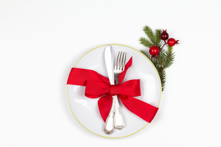 Christmas table place setting with plate, cutlery, pine branches,  ribbon and red berries. Winter holidays and festive background. Christmas eve dinner, New Year food lunch. View from above, top, horizontalの写真素材