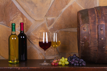 Red and white wine with grapes beside old cask in wine cellar. Wine and food conceptの写真素材
