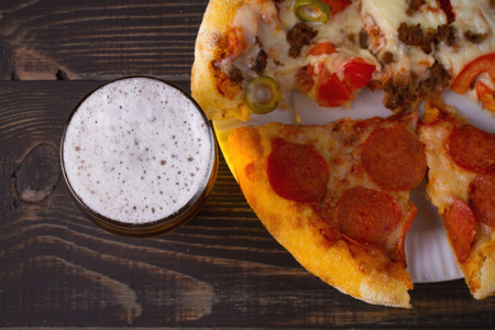 Beer and pizza on dark wooden background. Ale and food. View from above, top, horizontalの写真素材