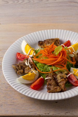 Chicken liver, carrot, eggs, tomatoes, lettuce and fried onion salad. Liver and vegetables. verticalの写真素材