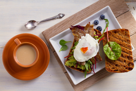 Poached egg, bacon, smashed white bean and avocado on toast. Sandwich. View from above, top, horizontalの写真素材