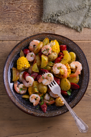 Shrimps with sausages, new potatoes and sweet corn. One sheet pan shrimps with sausages and vegetables. View from above, topの写真素材