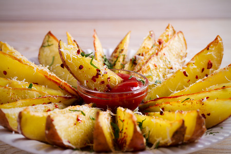 Garlic baked potato wedges with paprika and parmesan cheese. Potato fries on white plateの写真素材