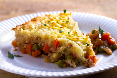 Classic homemade shepherd's pie (mashed potato and ground beef with vegetables) in white plate on wooden table. horizontalの写真素材