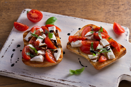 Caprese Bruschetta. Tomatoes, basil, mozzarella cheese with balsamic reduction drizzle on toast. Antipasto - starter dishの写真素材