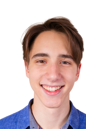 Handsome young man  looking at camera. Closeup portrait of teen boy in blue jeans shirt, isolated on white backgroundの写真素材