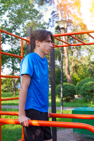 Sport. Young fit man exercising in park. Male doing pull ups on bars. Healthy lifestyle