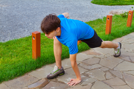 Young fit man exercising in park. Man doing stretching exercise, preparing for morning workout, running. Healthy lifestyleの写真素材