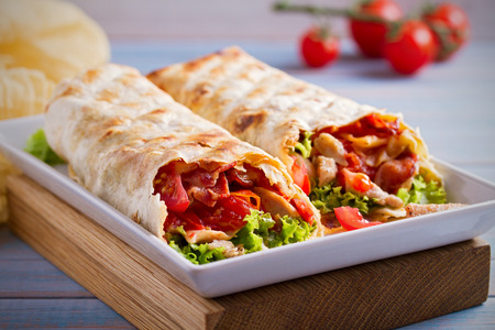 Chicken bacon wraps with tomatoes, lettuce and cheese. Tortilla, burritos, sandwiches twisted rolls. horizontalの写真素材