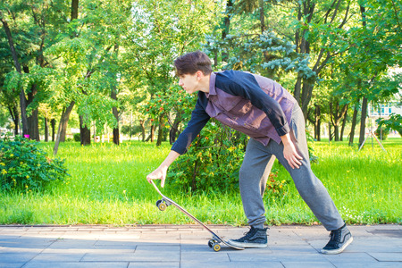 Young man with skateboard getting ready to skate in city park. Teen boy skaterの写真素材