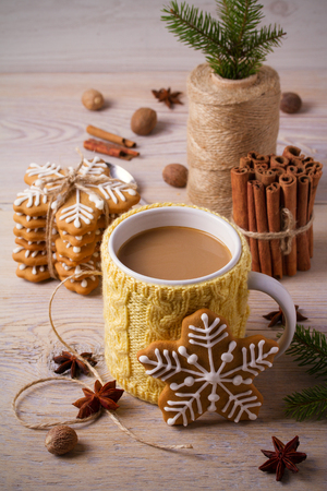 Knitted yellow cup with hot winter drink, cookies, cinnamon, decorations. Cozyの写真素材