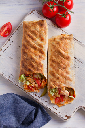 Chicken wraps with tomatoes, pickles, cabbage lettuce and onion. Tortilla, burritos, sandwiches, twisted rolls. overhead, verticalの写真素材