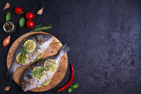 Sea bream or dorado  fish with lemon, herbs, vegetables and spices. Flatlay, overhead, copy spaceの写真素材