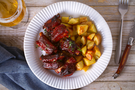 Grilled pork spare ribs with fries on white plate. Roasted sliced barbecue ribs. overhead, horizontalの写真素材