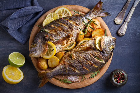 Roasted fish and potatoes, served on wooden tray. overhead, horizontal - imageの写真素材