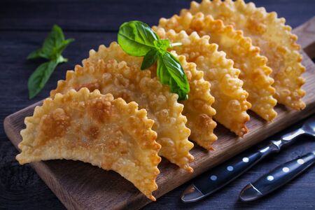 Chebureki - pan fried pies with meat and onions, served on wooden board. Fried-dough foodの写真素材